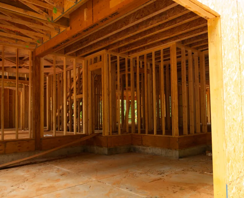Interior of a house under construction showing open wall studs, floor trusses and subfloor