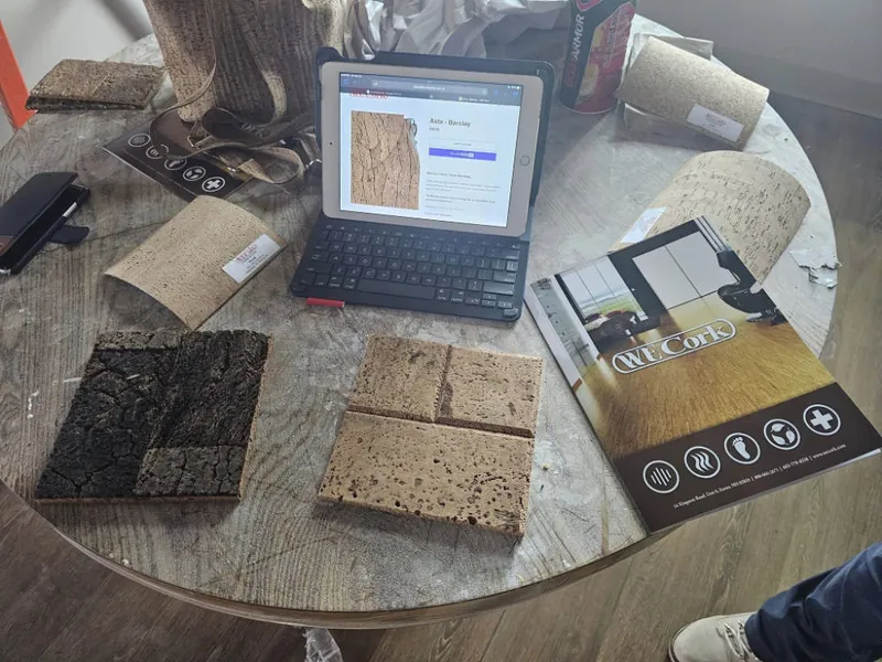 Tile, wood and metal finish samples on a table beside a laptop