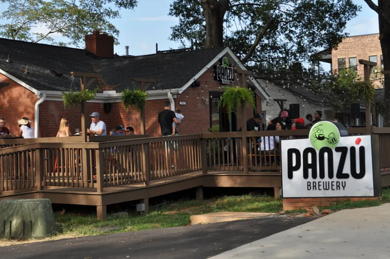 Completed wraparound wood deck and patio at Panzu Brewery in Mint Hill, with guests outside the renovated brick building