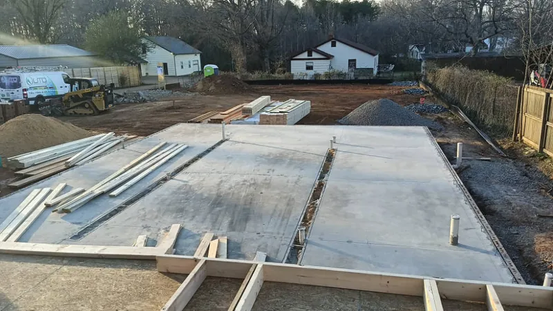 Freshly poured concrete slab and footings behind the brick house during the Panzu Brewery build