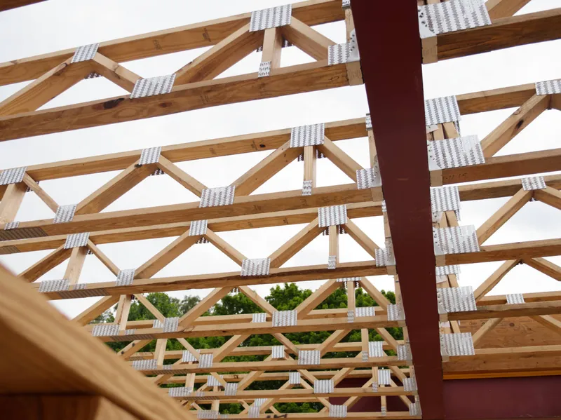 Close-up of engineered roof trusses against the sky on a framed building
