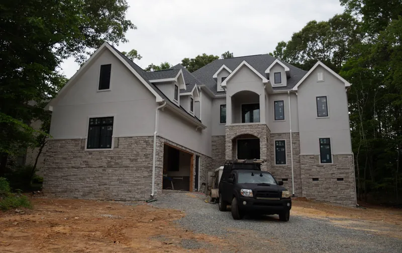Two-story custom home with stucco walls, stone veneer base and dormer windows, nearing completion